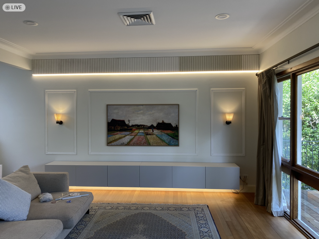 Feature wall with recessed LED strip, floating cabinet underglow and symmetrical wall sconces flanking a framed TV